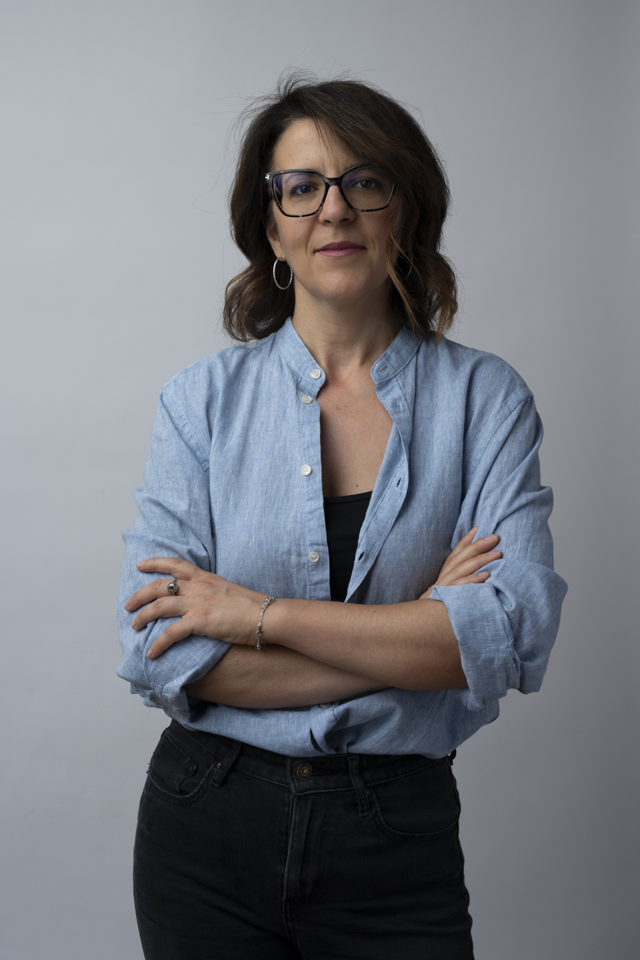 Fotografia in studio di donna Ritratto fotografico professionale di donna con braccia incrociate su sfondo chiaro.