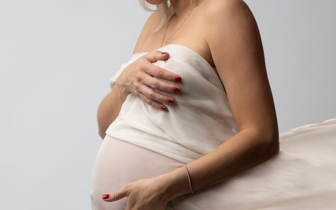 Servizio fotografico di maternità in studio, futura mamma bionda con velo bianco in movimento